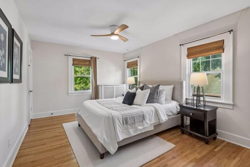 bedroom with hardwood floors, ceiling fan and multiple windows.