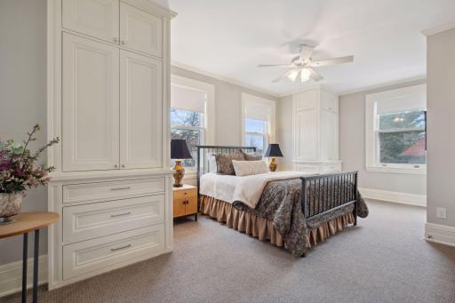 Spacious primary bedroom with ceiling fan, abundant natural light, and spa-like bathroom