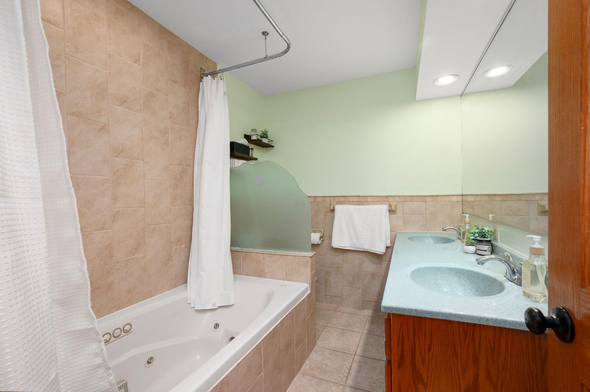 main bath complete with tiled tub/shower combination, wide vanity counter, and tile floor