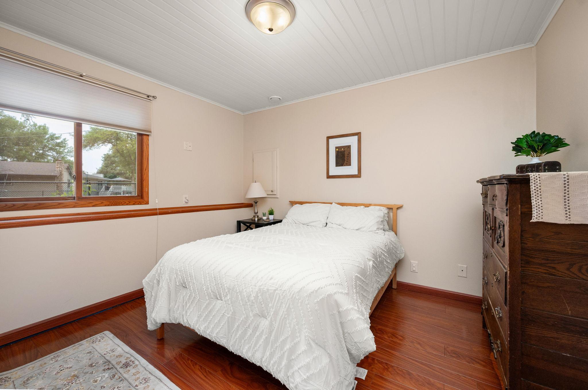 Comfortable lower-level bedroom featuring warm wood trim accents, light wall tones, and cozy lighting