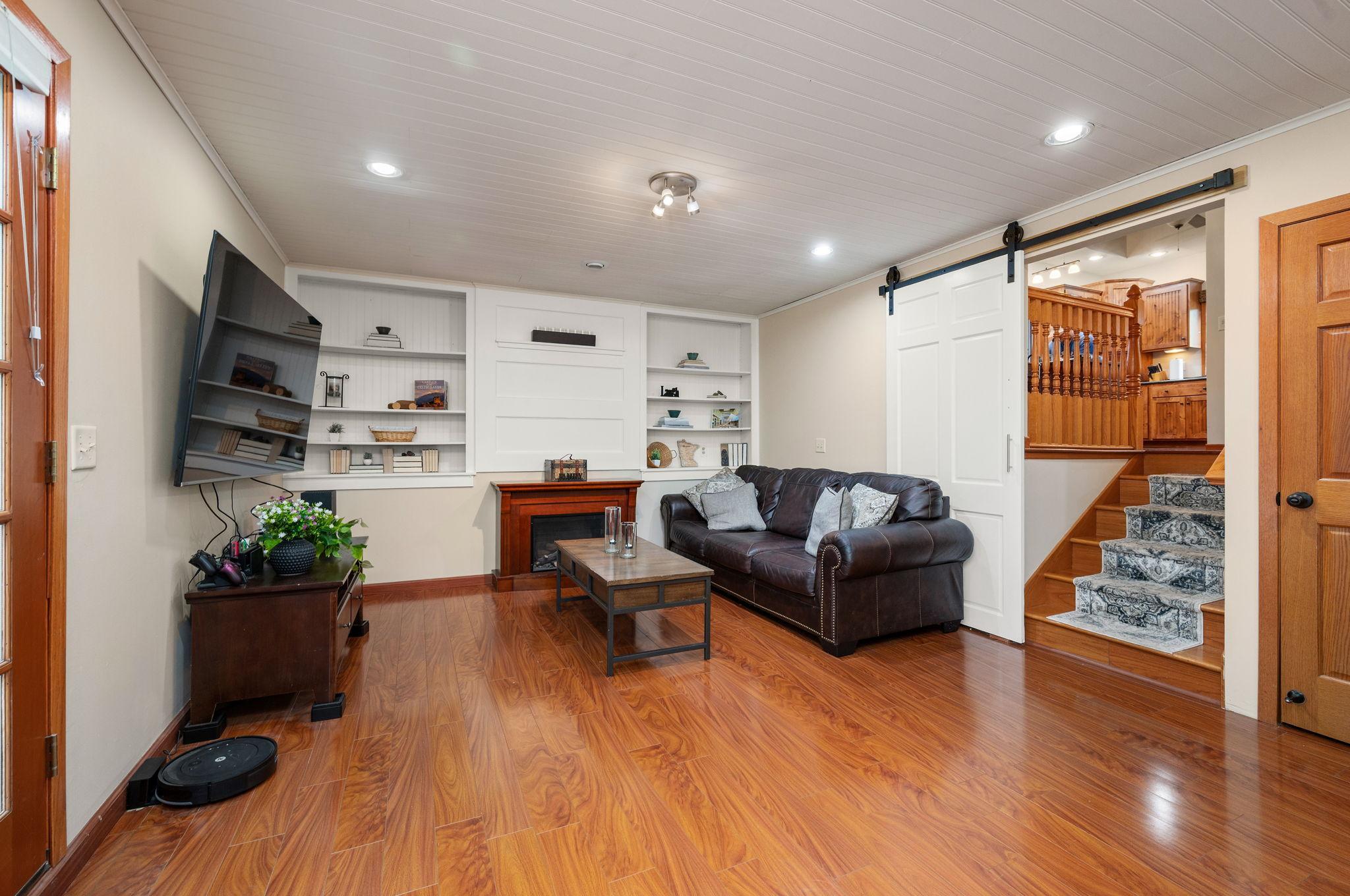 : Warm lower-level family room featuring built-in shelving, and a sliding barn door accent