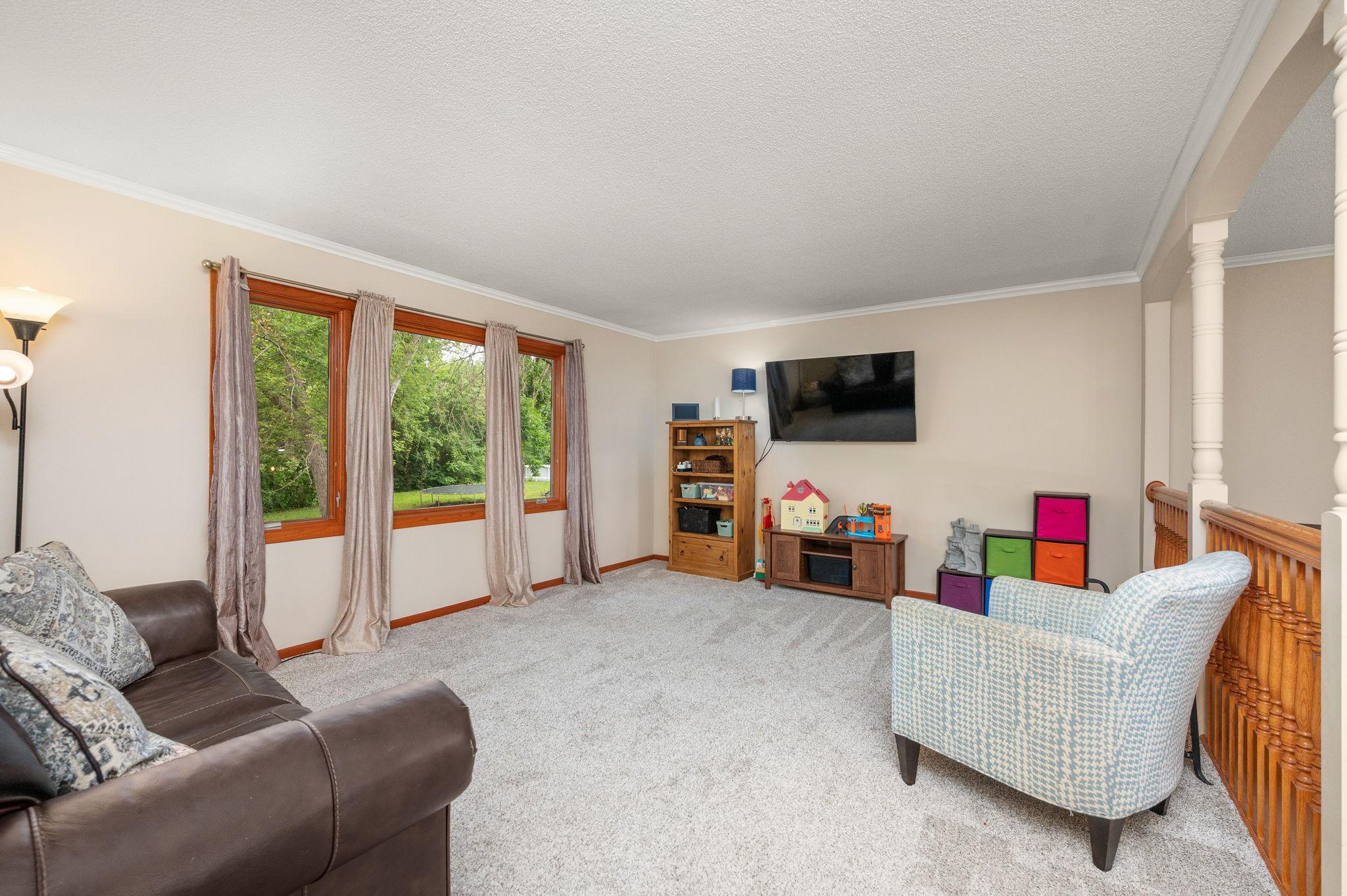 Sunlit main-level living room featuring wall-to-wall windows and nature views