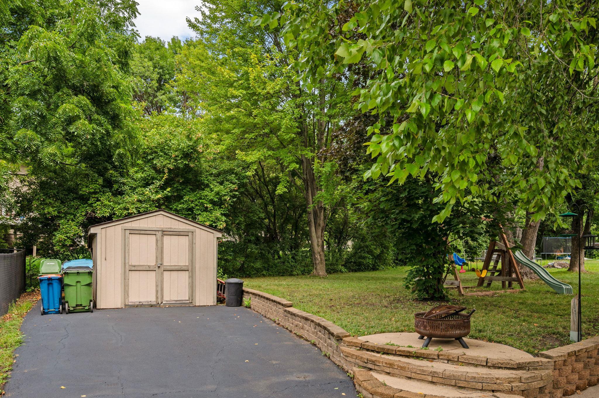 Outdoor storage shed nestled along the lush tree line, offering extra space for lawn equipment and tools
