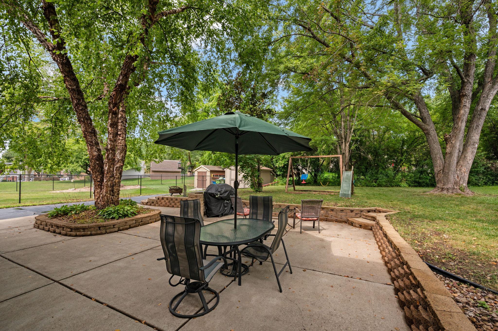 Spacious stamped concrete patio featuring a dining set with umbrella and grill setup, perfect for outdoor entertaining