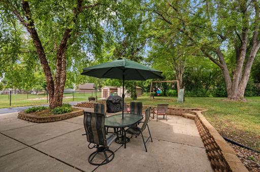 Spacious stamped concrete patio featuring a dining set with umbrella and grill setup, perfect for outdoor entertaining
