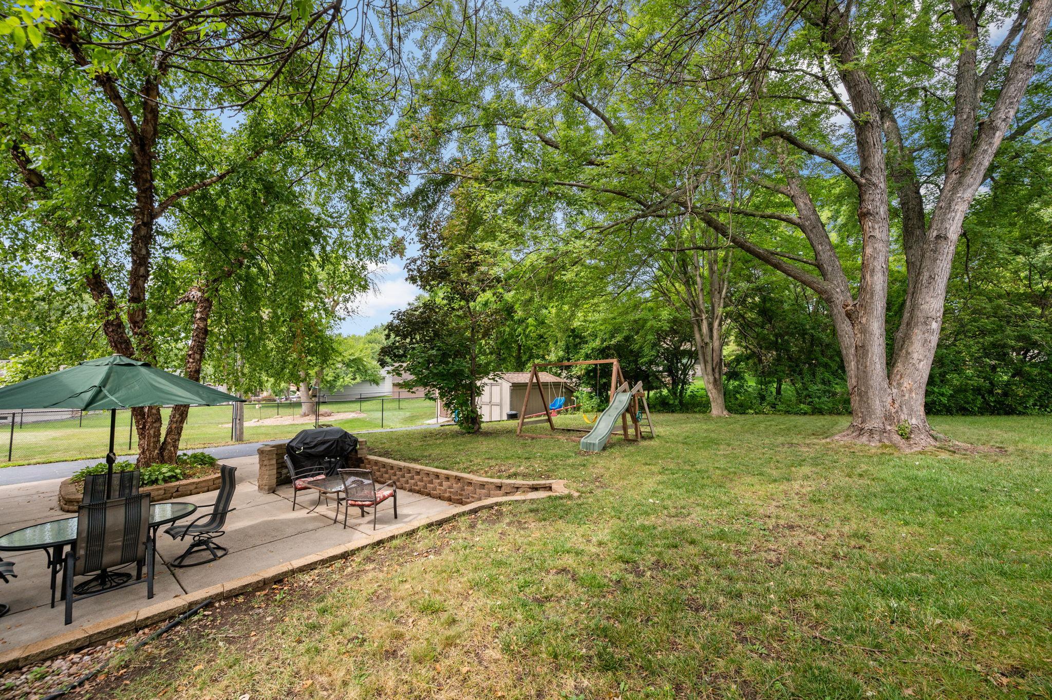 Broad view of the retaining wall patio leading out to a level green lawn and play area