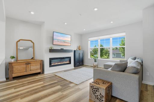 The cozy living room is anchored by a modern fireplace, creating the perfect place to relax year-round. Luxury vinyl plank flooring flows seamlessly throughout the main and upper levels, adding warmth, durability, and style.