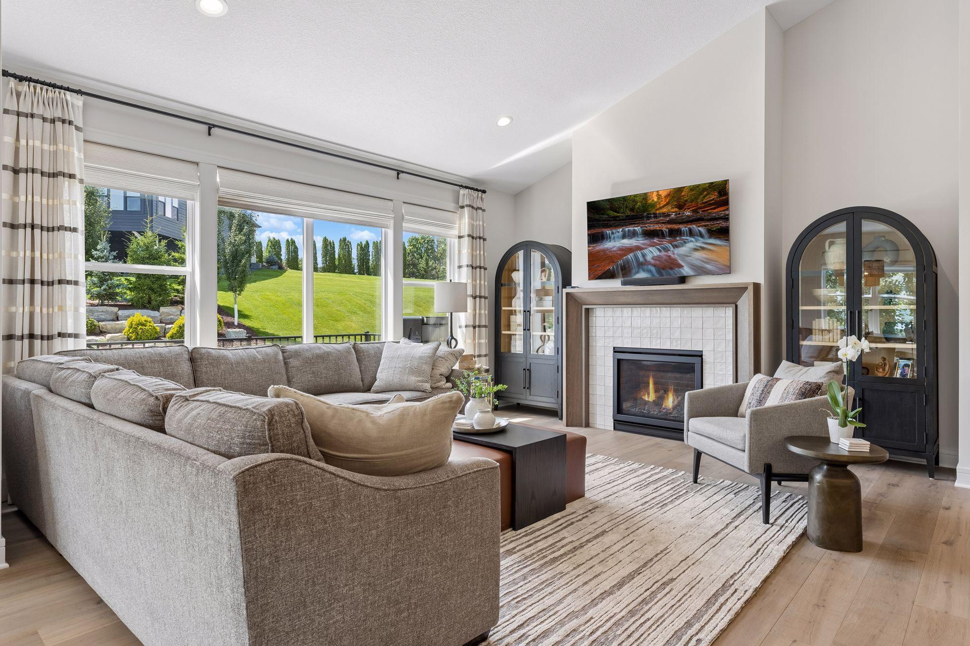 Inviting family room featuring vaulted ceilings, a gas fireplace with designer tile surround, custom window coverings, and an abundance of natural light.
