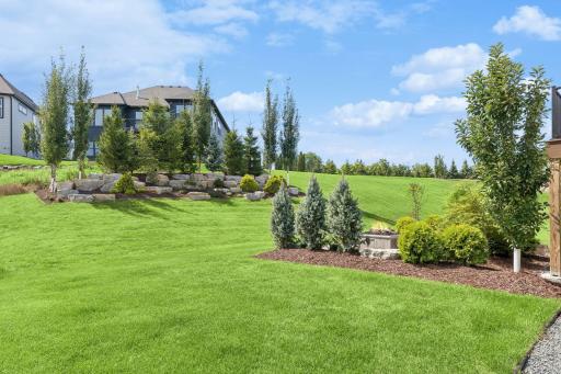 The tree-lined landscaping berm with outcroppings allows backyard privacy.