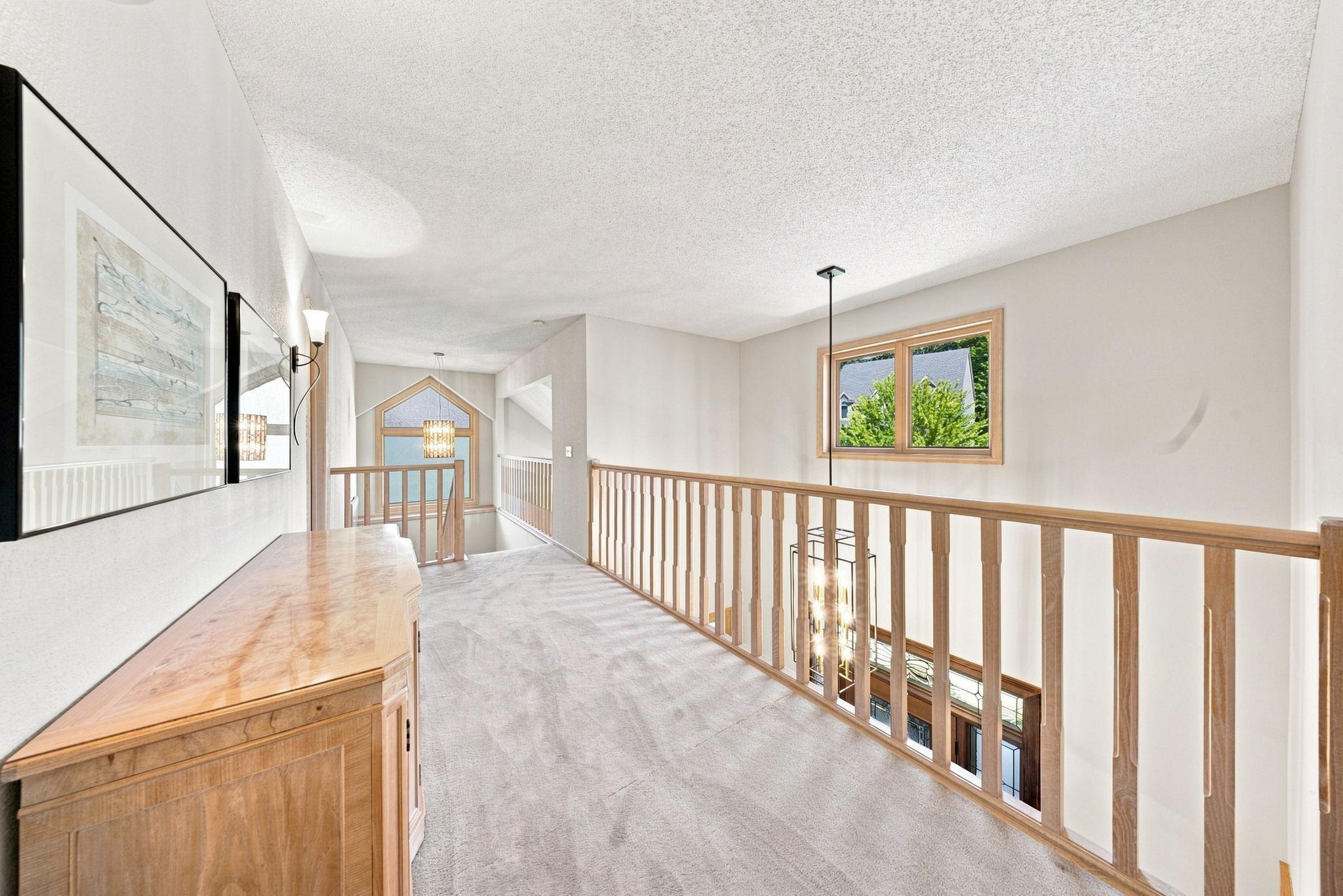 The catwalk opens to the foyer and separates the primary bedroom from the other three bedrooms in the upper level