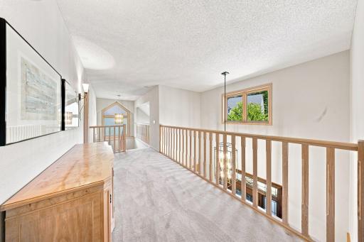 The catwalk opens to the foyer and separates the primary bedroom from the other three bedrooms in the upper level