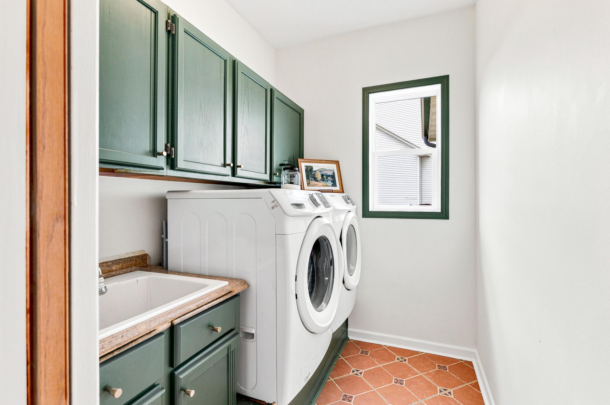 Convenient main-level laundry room with utility sink, abundant cabinetry, and plenty of space to keep everyday tasks organized.