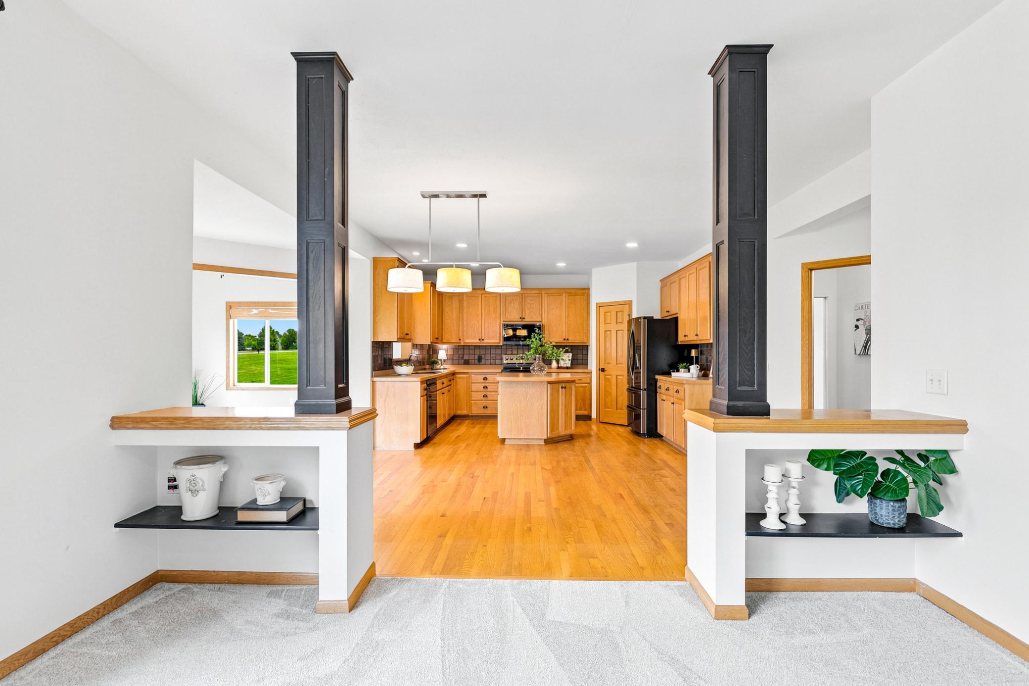 Architectural columns and custom display niches create an elegant transition from the great room to the spacious chef's kitchen, blending openness with timeless character.