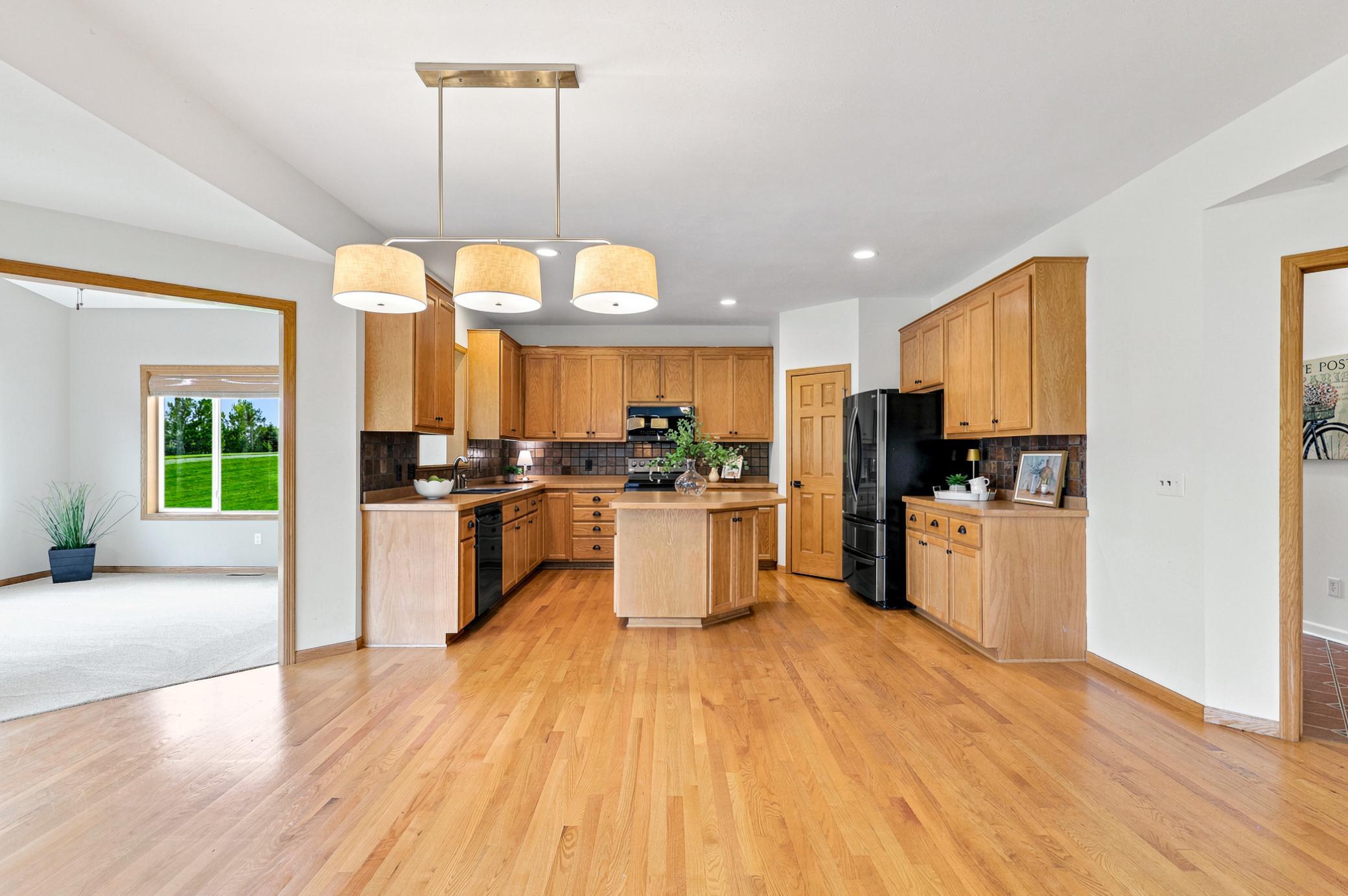 The heart of the home features abundant oak cabinetry, hardwood floors, a center island, generous prep space, pantry, and an open layout perfect for everyday living and entertaining.