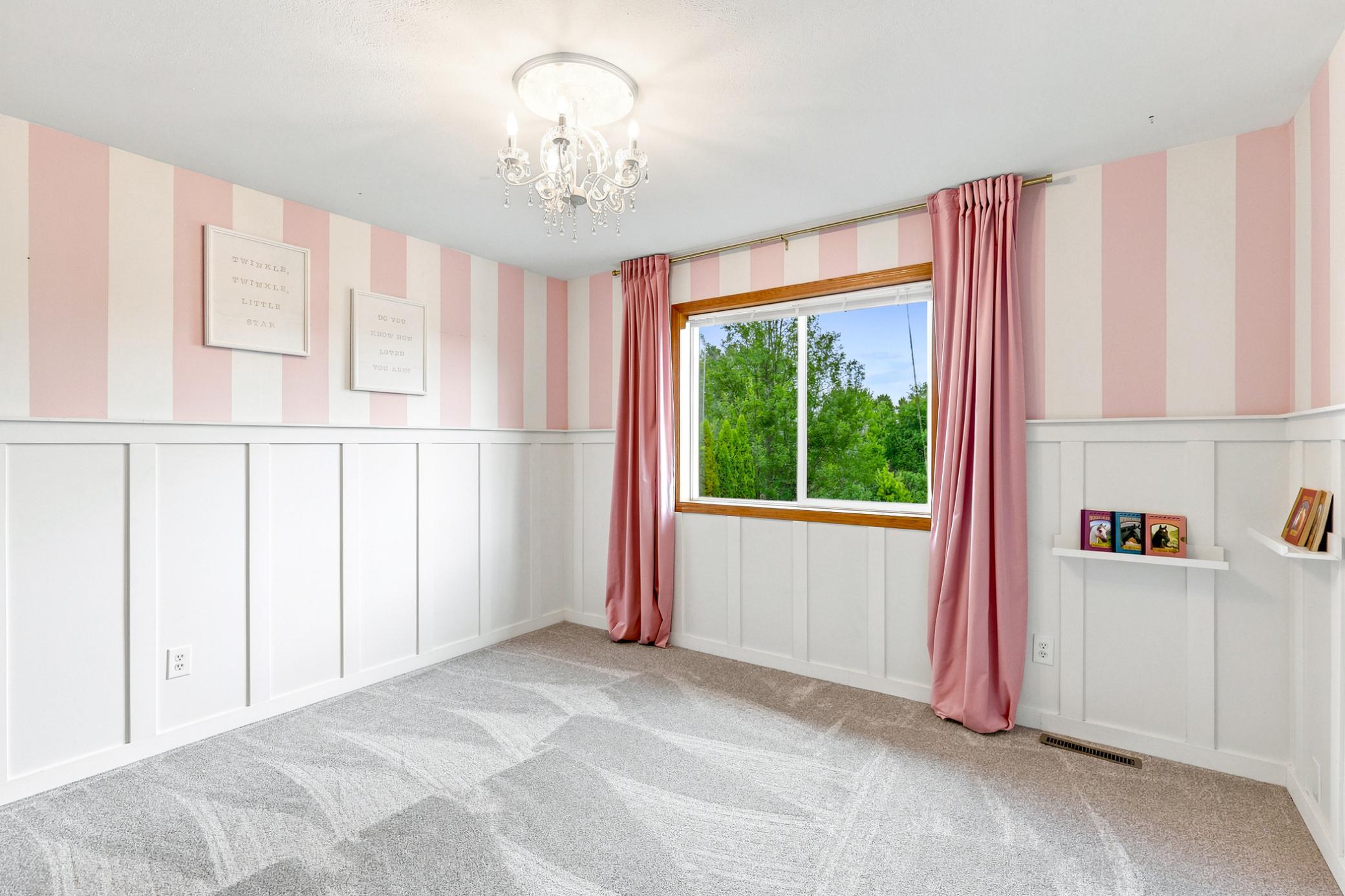 Charming third bedroom upstairs with custom board and batten detailing, designer accent wall, elegant lighting, and abundant natural light.