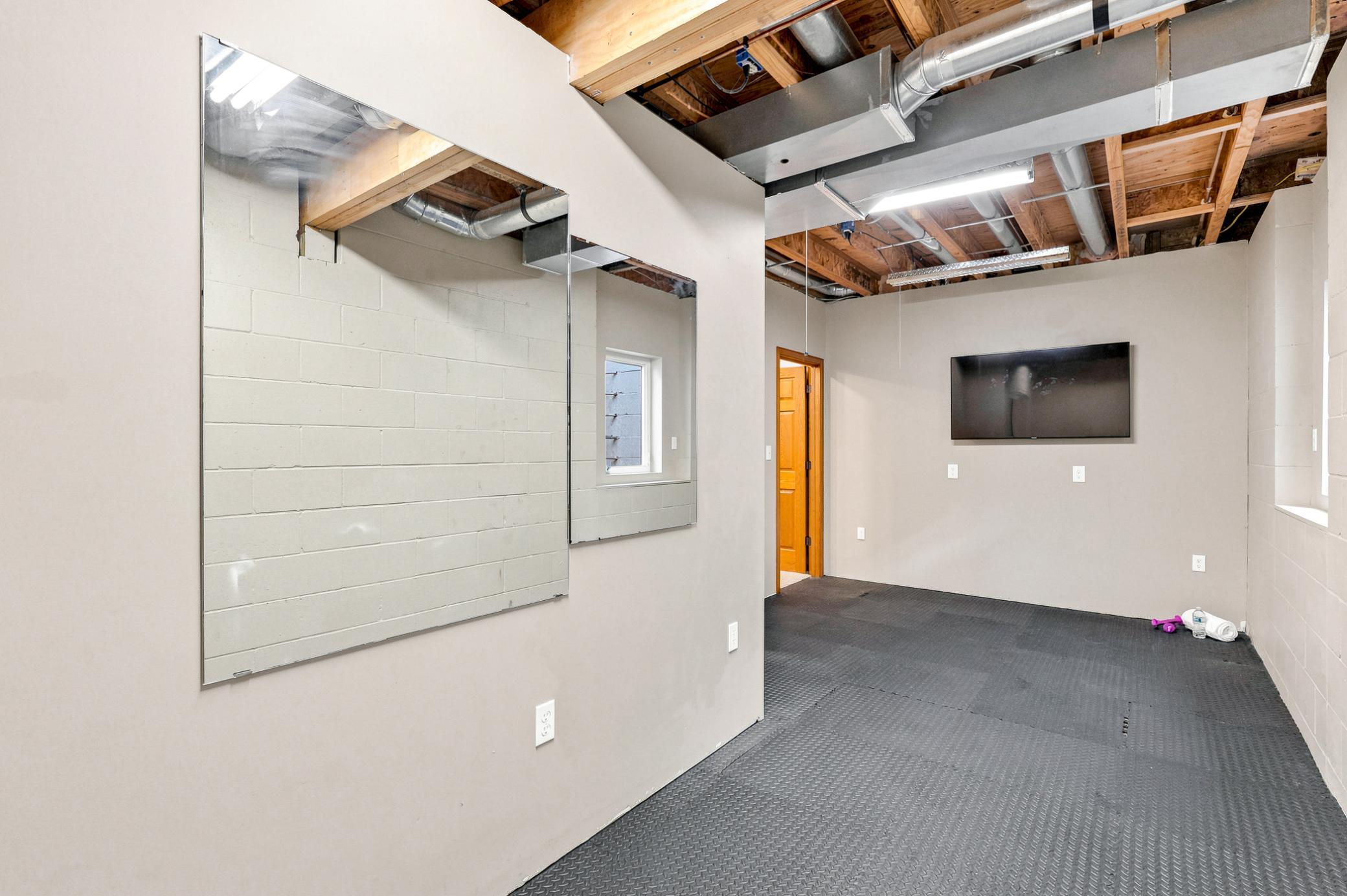 Dedicated exercise space with durable flooring and wall-mounted TV, easily adaptable as a home gym, hobby room, workshop, or versatile flex space to fit your lifestyle.