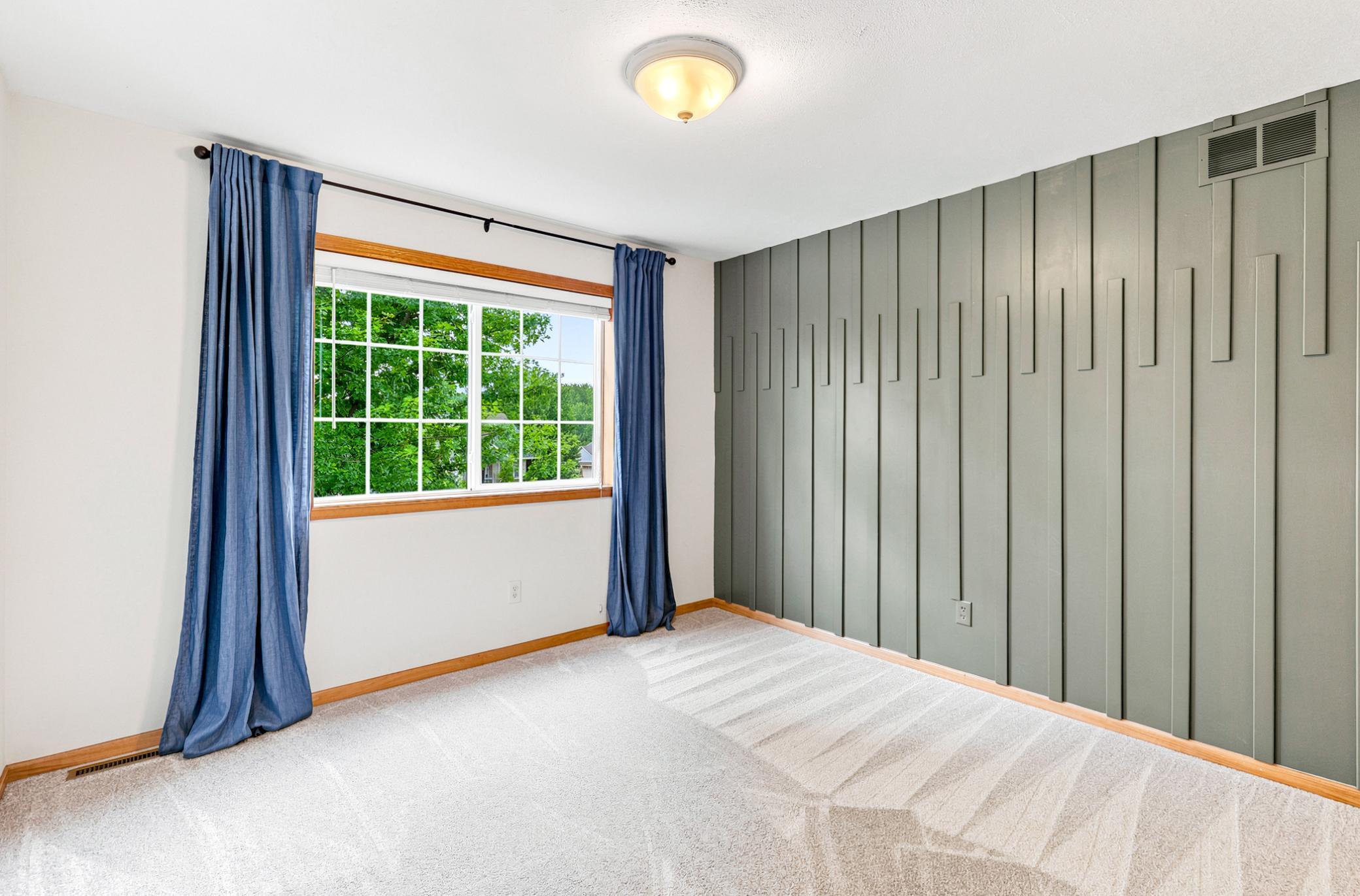 Spacious fourth bedroom upstairs featuring a custom designer accent wall, plush carpeting, generous closet space, and abundant natural light—perfect for family, guests, or a home office.