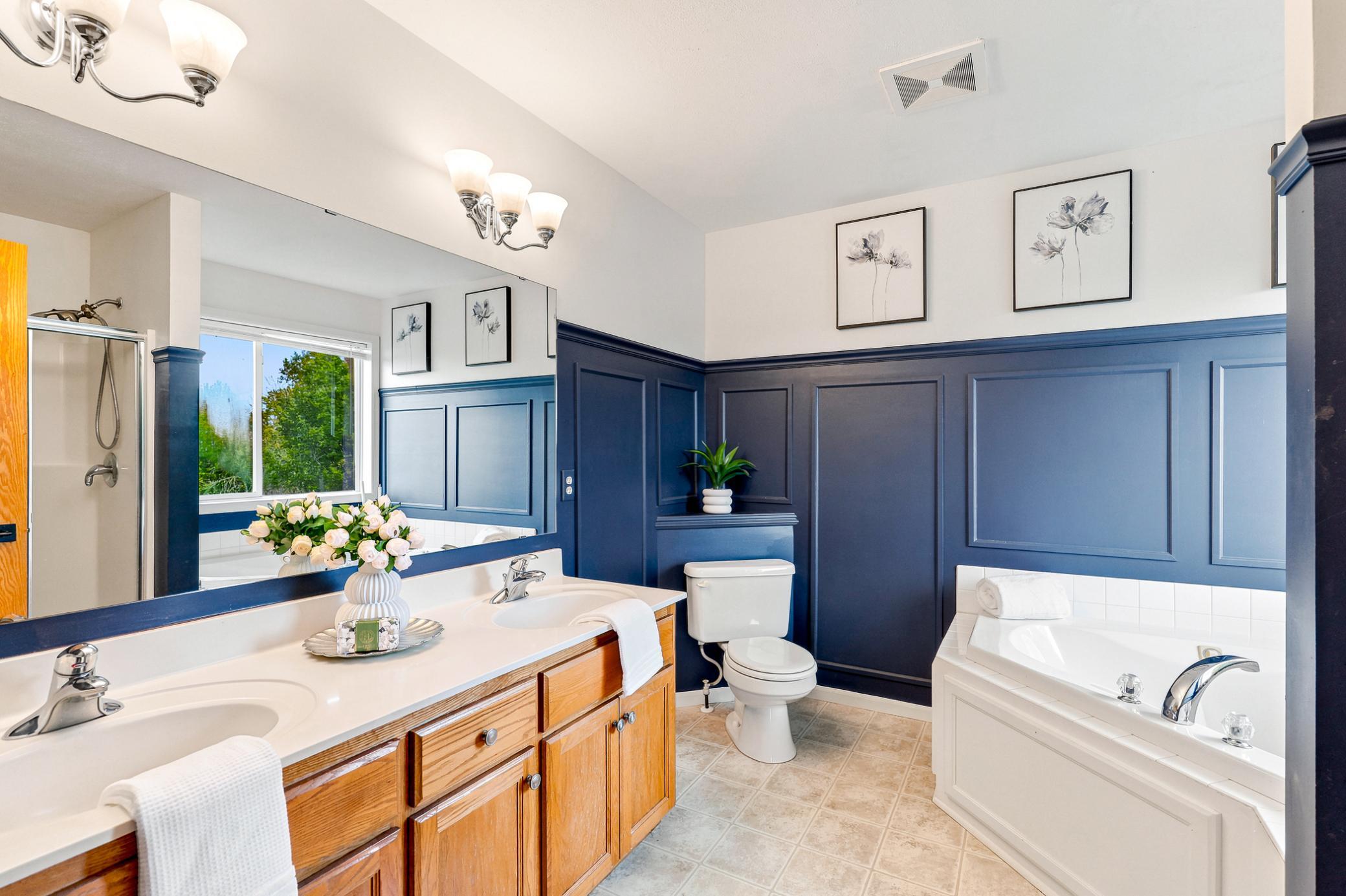 The private primary bath features dual vanities, a relaxing jetted soaking tub, separate walk-in shower, and a spacious layout that creates a true owner's retreat.
