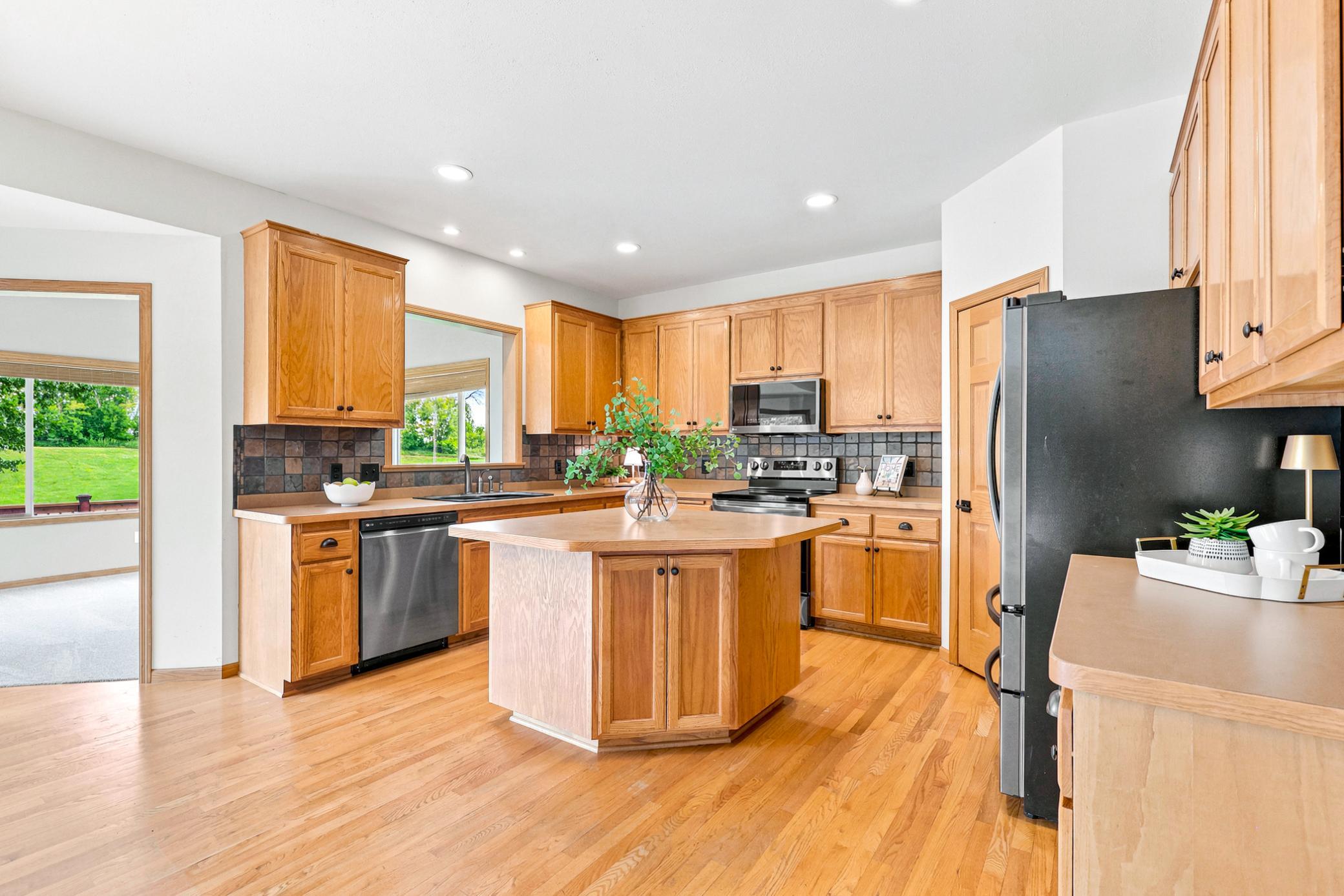 The beautifully appointed kitchen features stainless steel appliances, a center island, hardwood floors, and expansive workspace for cooking, gathering, and entertaining.