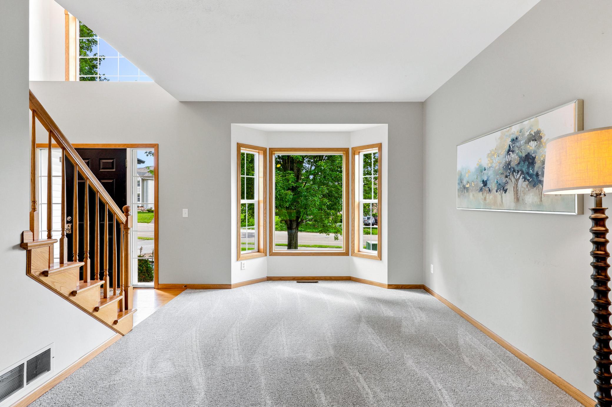 Walls of windows and a dramatic two-story ceiling fill the living room with natural light, while the open layout provides a seamless flow into the heart of the home.