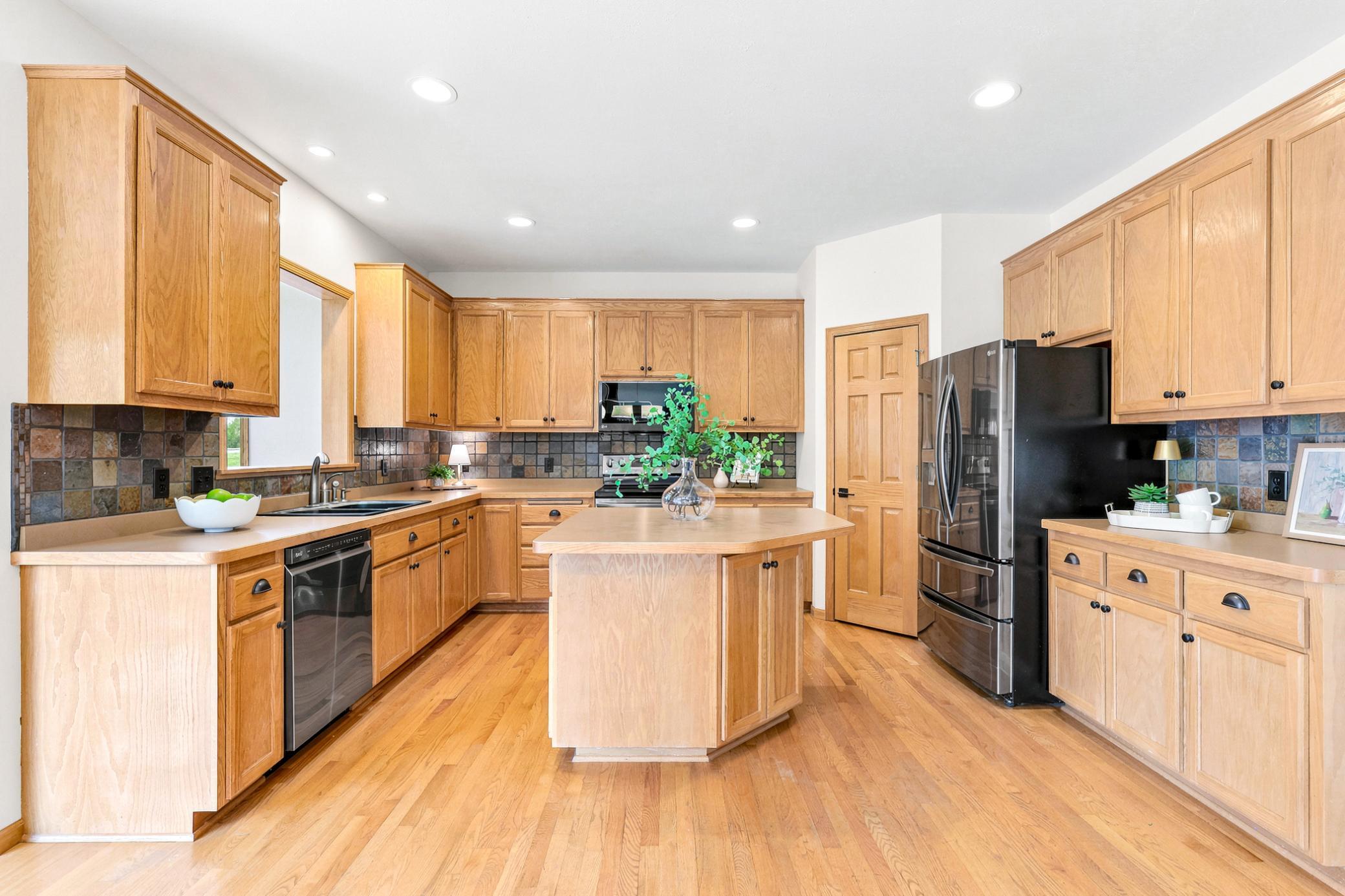 The heart of the home features abundant oak cabinetry, hardwood floors, a center island, generous prep space, pantry, and an open layout perfect for everyday living and entertaining.