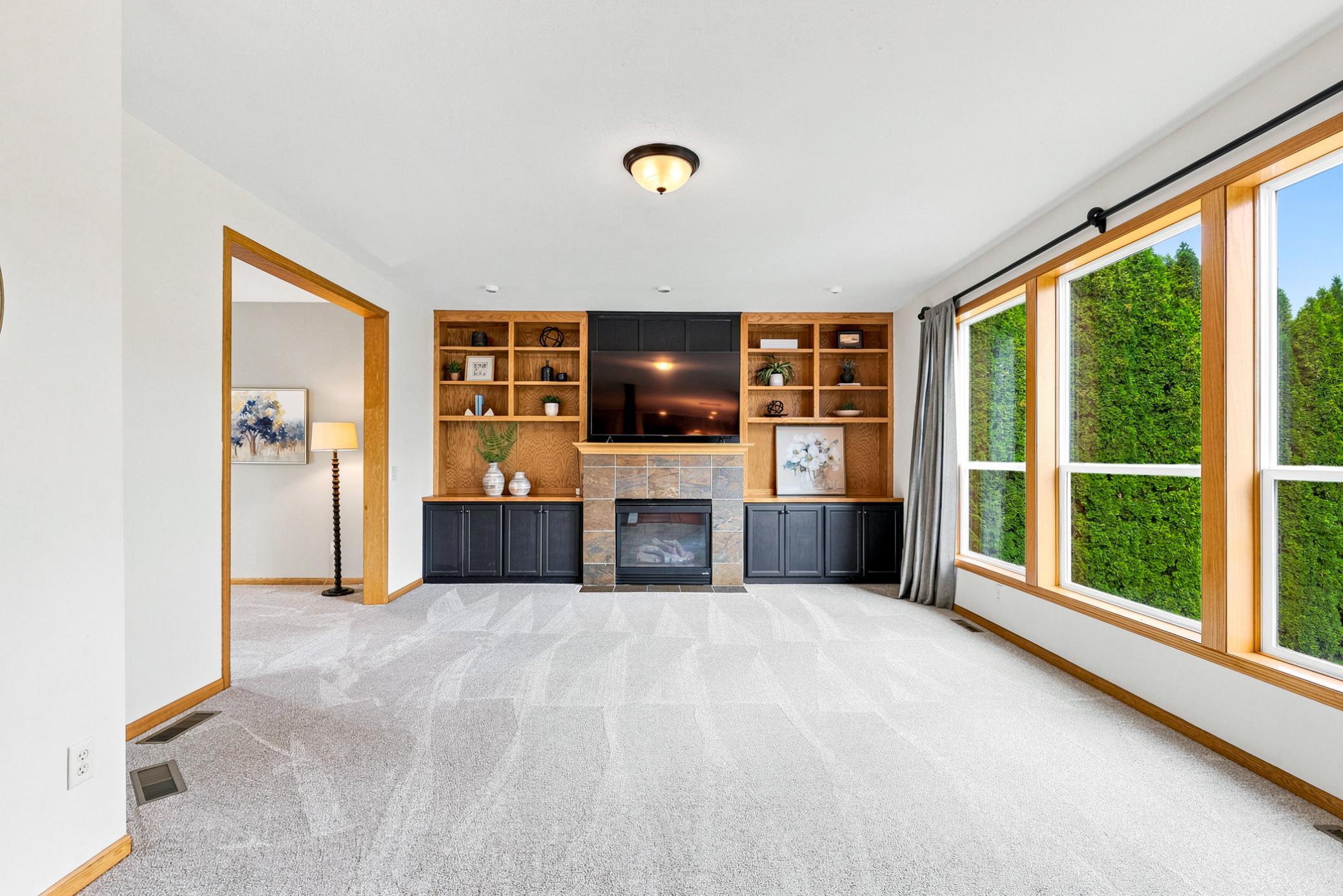 The inviting great room showcases custom built-in cabinetry, a cozy gas fireplace, oversized windows, and abundant natural light—creating the perfect gathering space for family and friends.