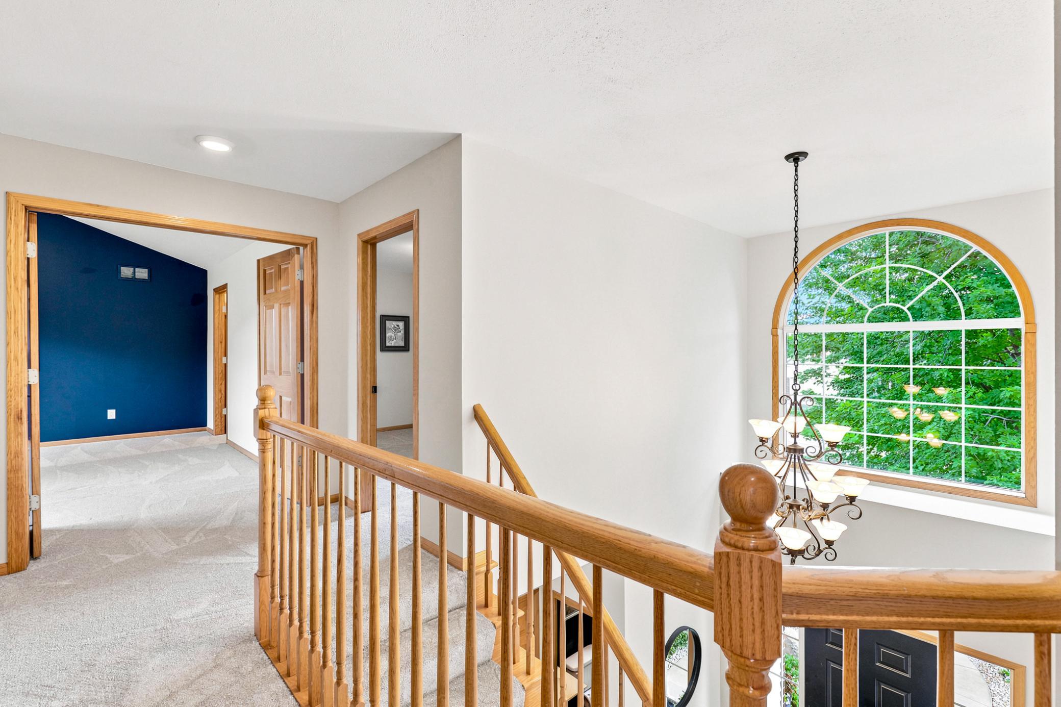 The open upper-level landing overlooks the dramatic two-story foyer and features a stunning arched picture window that fills the home with natural light and architectural charm.