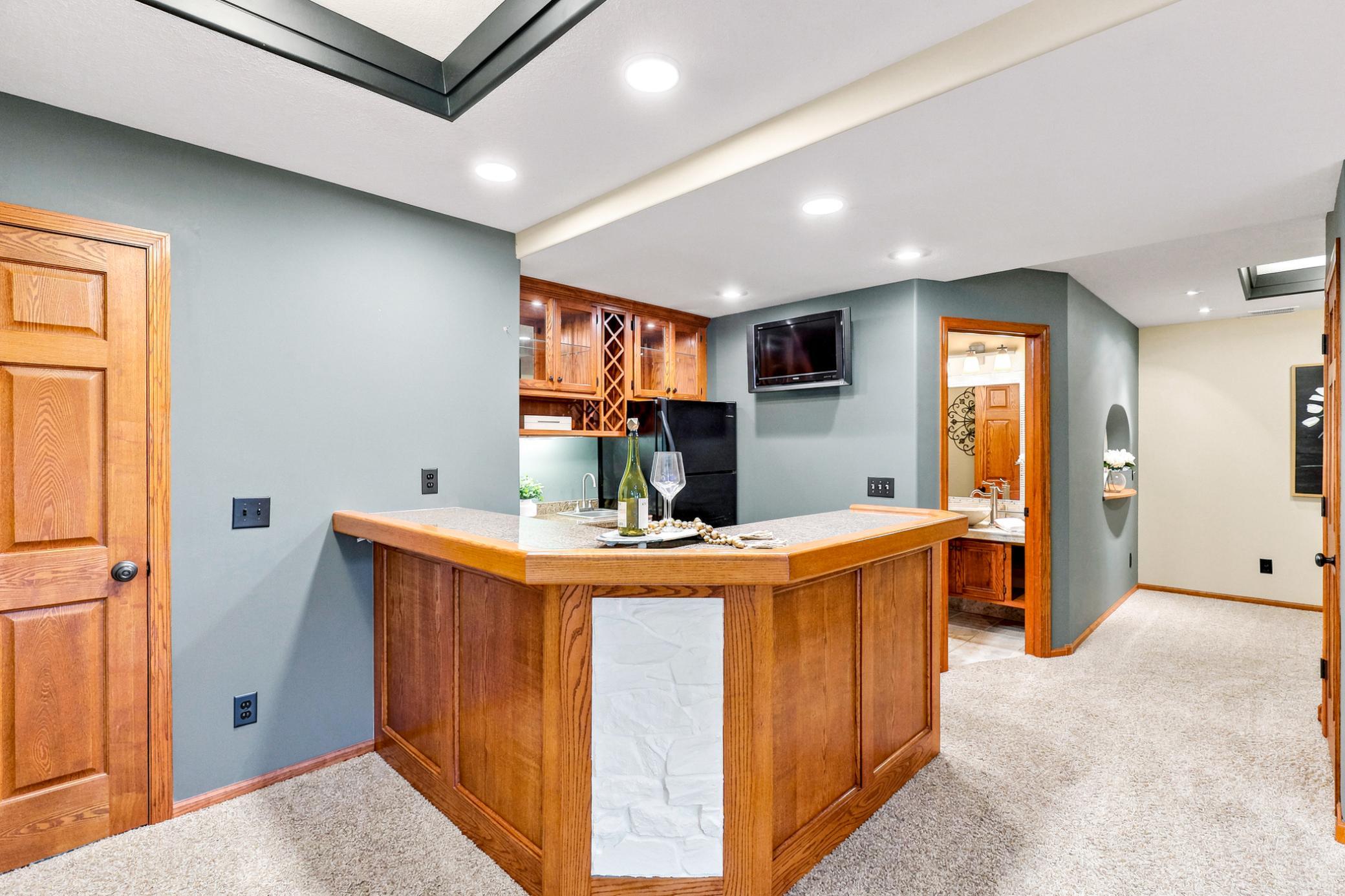 The beautifully appointed wet bar serves as the centerpiece of the lower level, offering generous seating, abundant cabinetry, and seamless access to the recreation room and adjacent ¾ bath.