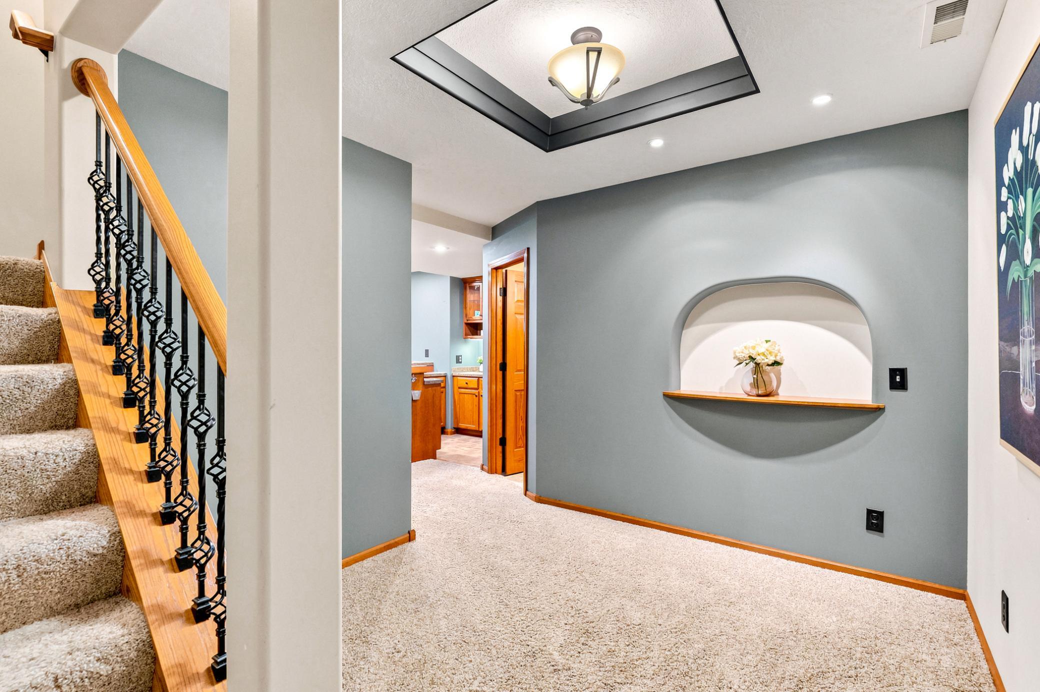 The inviting lower-level landing showcases elegant architectural details, custom display niche, and a warm, welcoming transition into the beautifully finished lower level.
