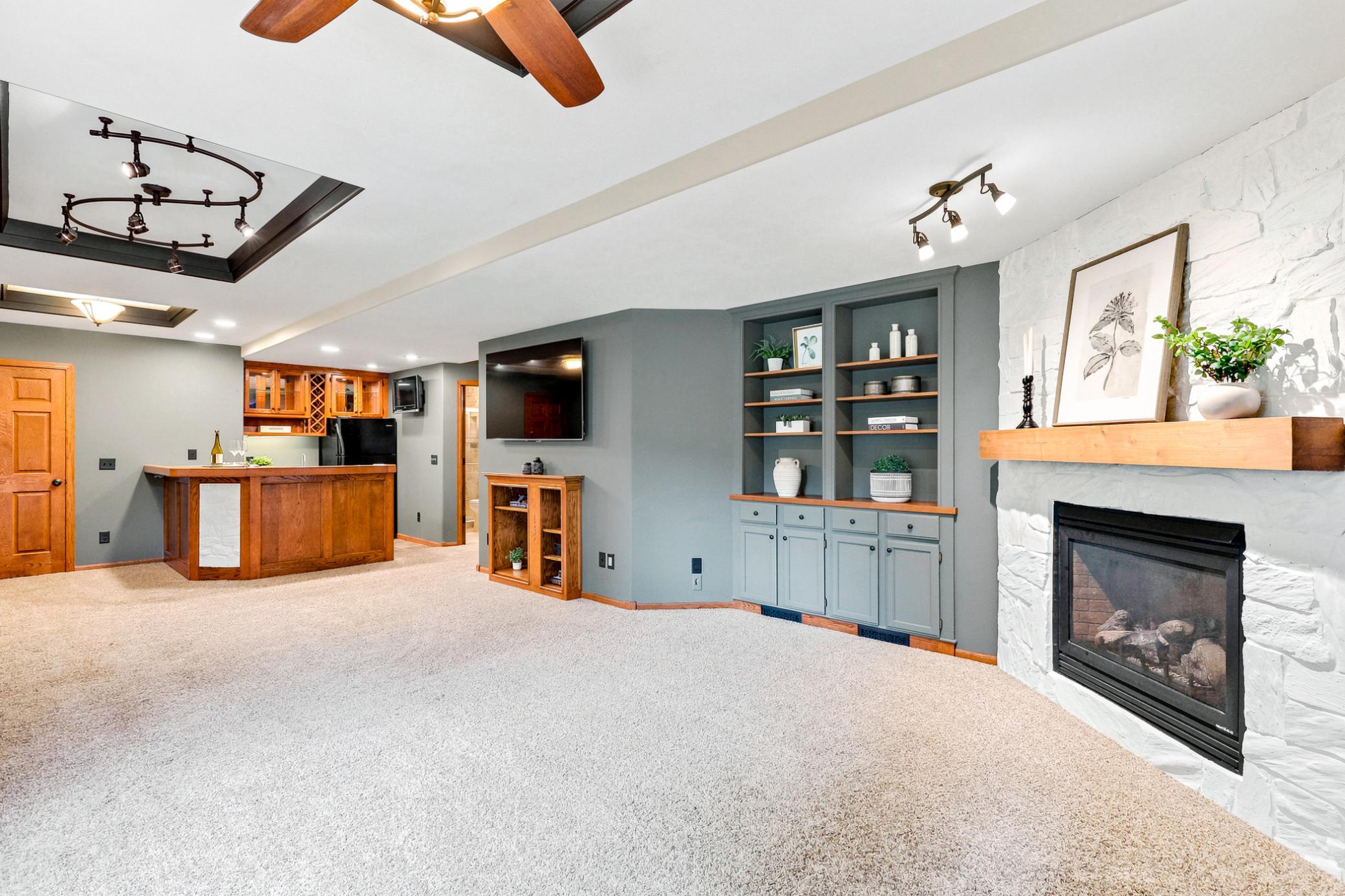 The expansive walkout lower level is designed for entertaining, featuring a custom wet bar, built-in media center, striking stone gas fireplace, and abundant space for relaxing or hosting family and friends.