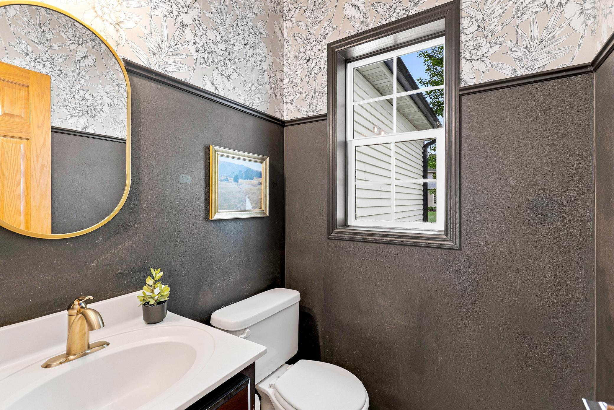 Stylish main-level powder bath featuring designer wallpaper, updated fixtures, and a window that fills the space with natural light.