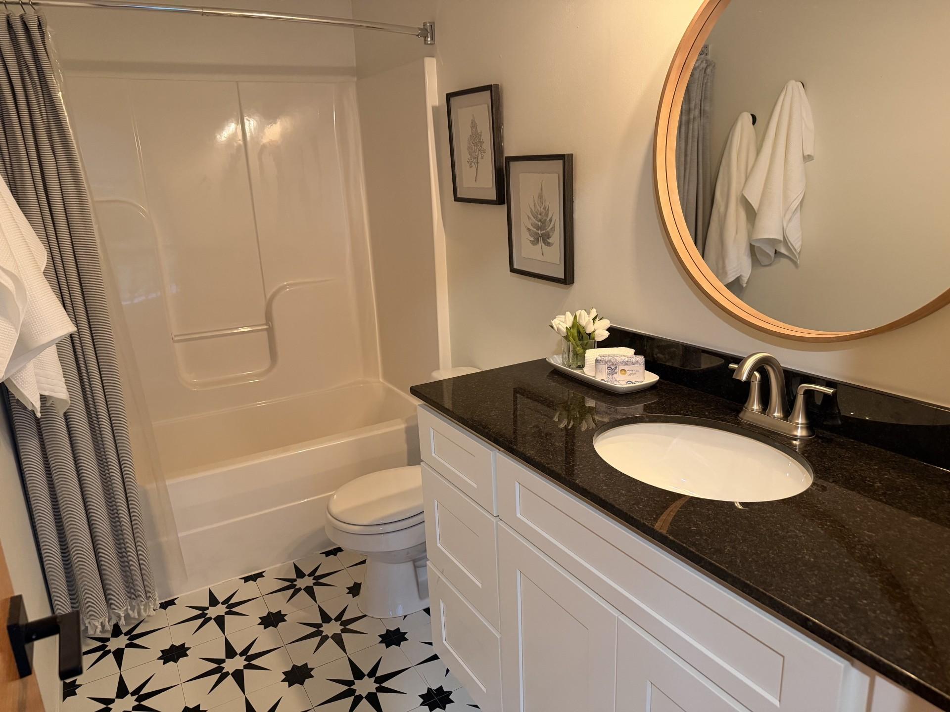 The spacious upper-level full bathroom is thoughtfully designed to comfortably serve the home's three secondary bedrooms. It features a large single-sink vanity with granite countertops, crisp white cabinetry, updated brushed nickel fixtures, durable