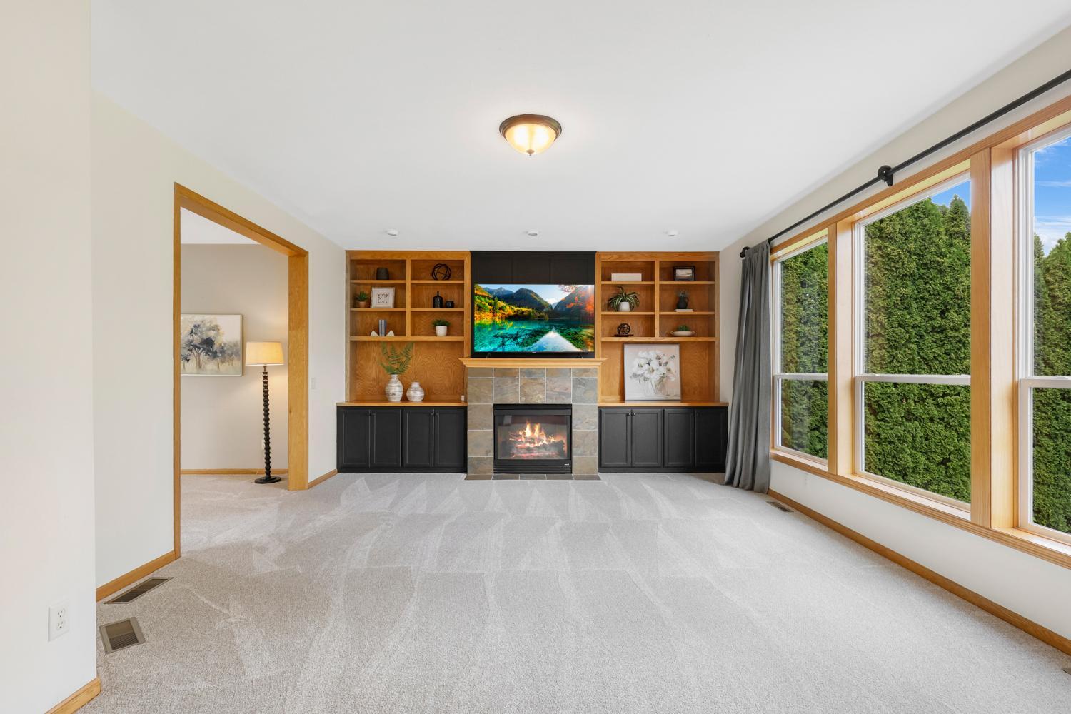The inviting great room showcases custom built-in cabinetry, a cozy gas fireplace, oversized windows, and abundant natural light—creating the perfect gathering space for family and friends.