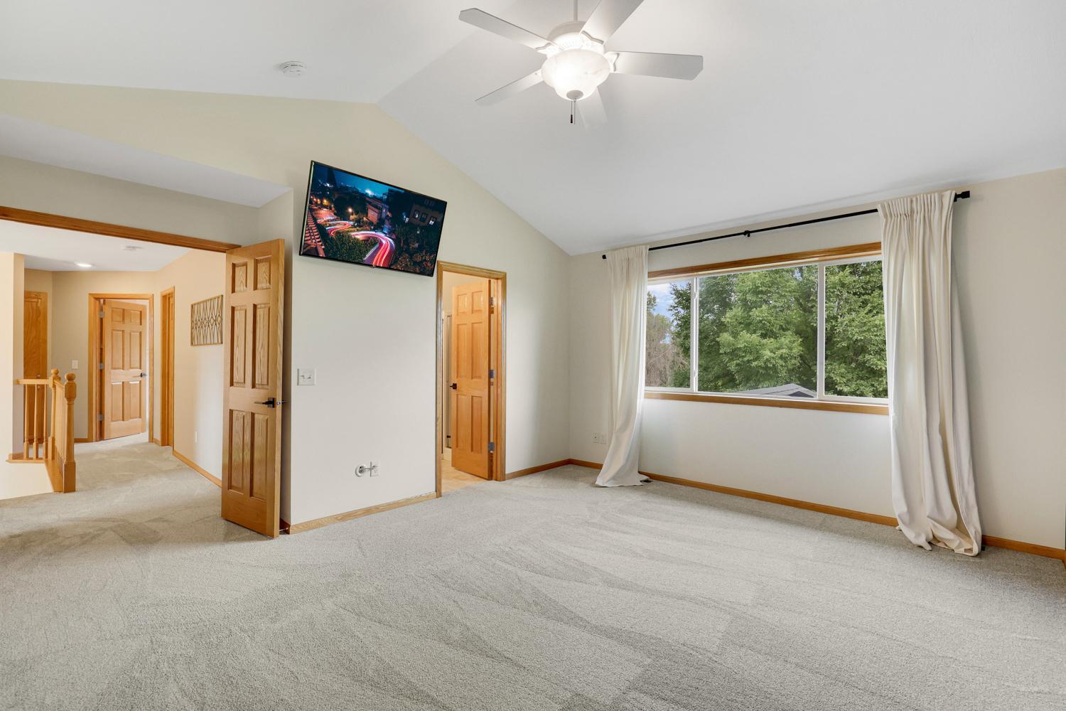 The expansive primary bedroom offers room for a king-sized suite, a vaulted ceiling with ceiling fan, and a peaceful atmosphere designed for relaxation.