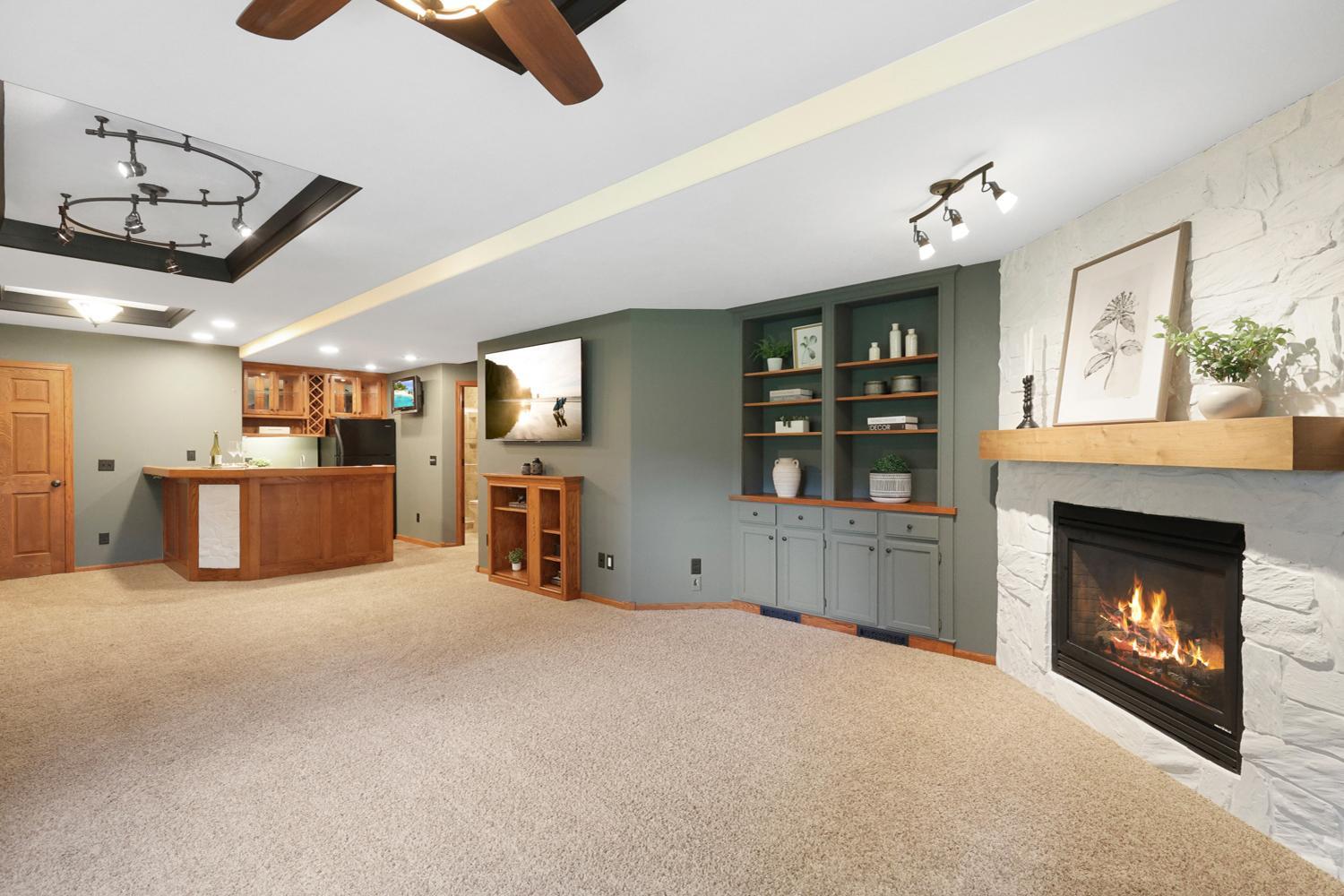 The expansive lower level is designed for entertaining, featuring a custom wet bar, built-in media center, striking stone gas fireplace, and abundant space for relaxing or hosting family and friends.