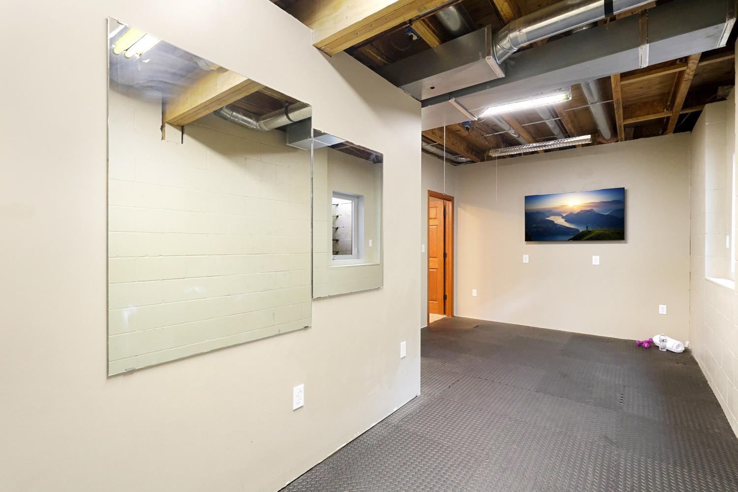 Dedicated exercise space with durable flooring and wall-mounted TV, easily adaptable as a home gym, hobby room, workshop, or versatile flex space to fit your lifestyle.