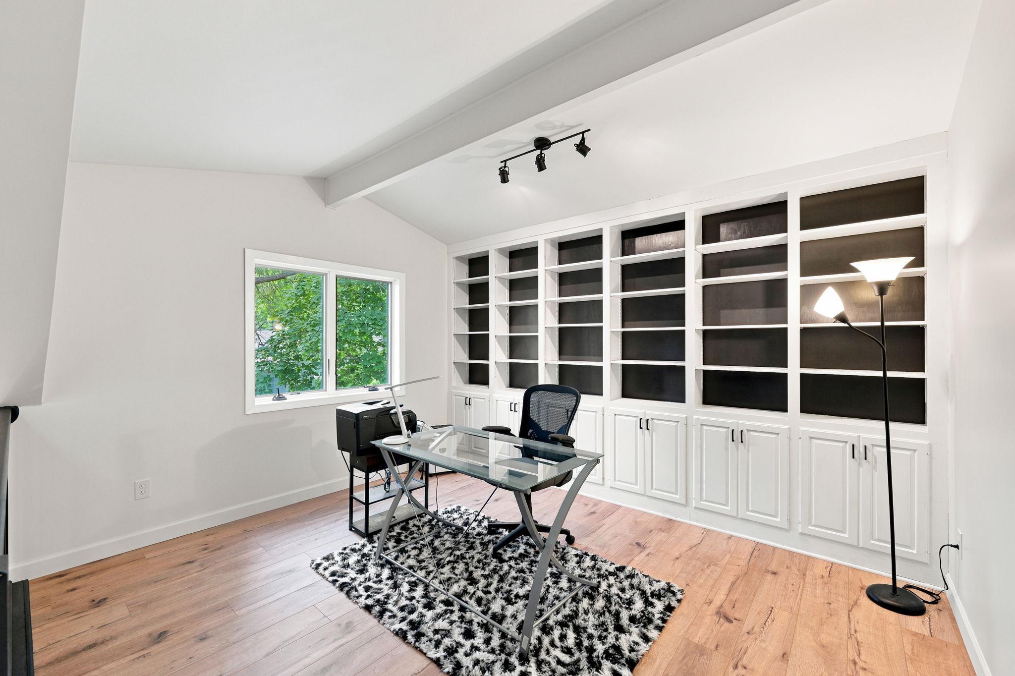Wonderful loft/library features a full wall of bookcases and enclosed cabinets! A perfect location for a home office or an upper level family room!
