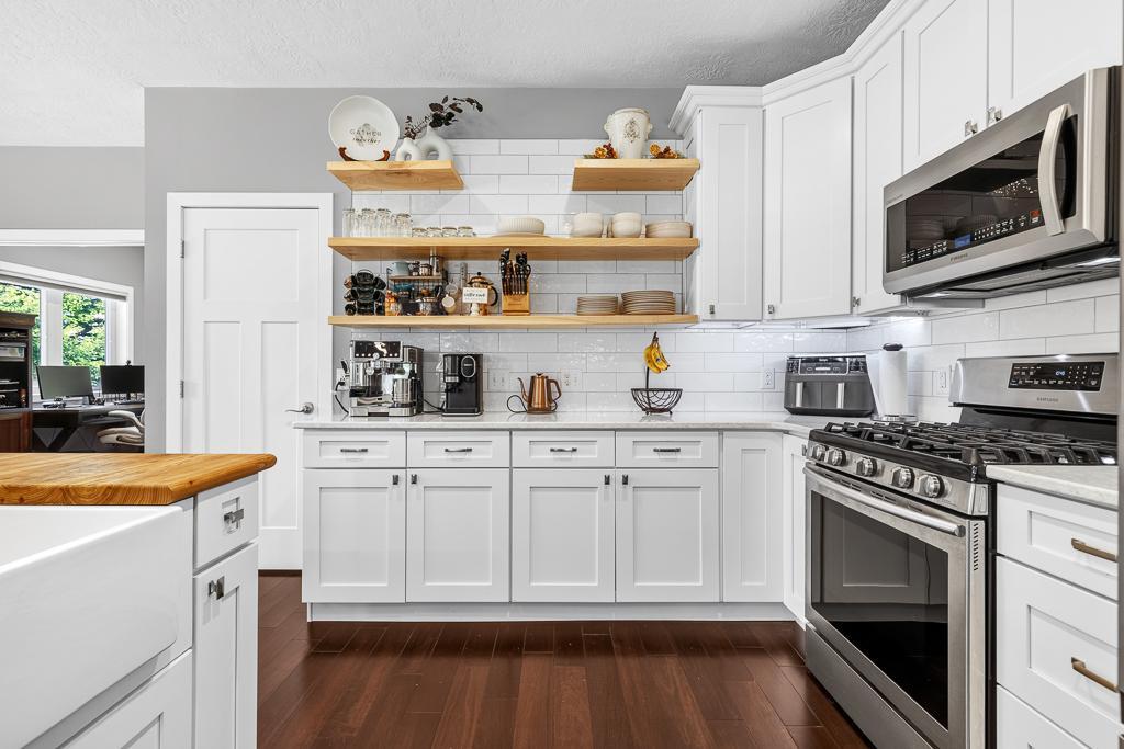 The floating shelves offer a warm contrast to the bright white subway tile and cabinets