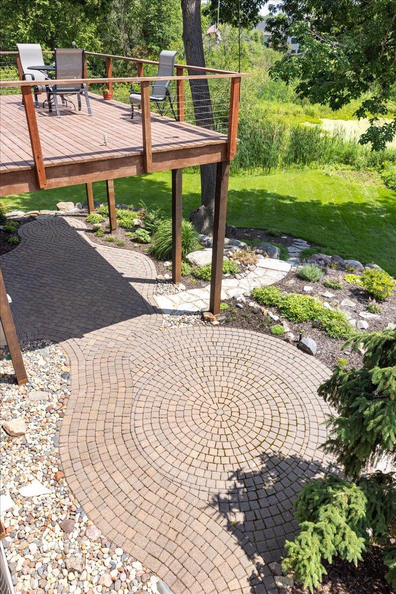 Whimsical flagstone patios, winding stone pathways, and handcrafted stone steps weave through the landscape, creating a storybook-like outdoor setting that blends seamlessly with the home's private wooded surroundings.