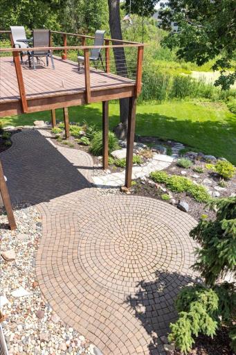 Whimsical flagstone patios, winding stone pathways, and handcrafted stone steps weave through the landscape, creating a storybook-like outdoor setting that blends seamlessly with the home's private wooded surroundings.