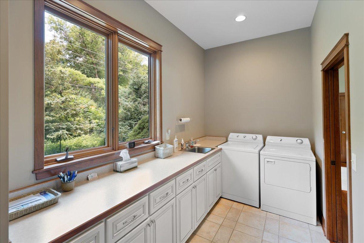 Ideally located between the kitchen and the garage entry, the mudroom / laundry is both practical and spacious, featuring abundant cabinetry, coveted countertop space for folding and organization, and coat closet to keep everyday essentials stored.