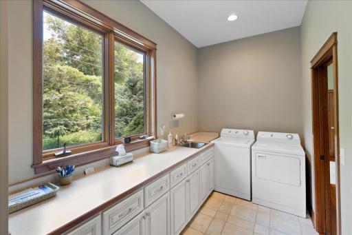 Ideally located between the kitchen and the garage entry, the mudroom / laundry is both practical and spacious, featuring abundant cabinetry, coveted countertop space for folding and organization, and coat closet to keep everyday essentials stored.