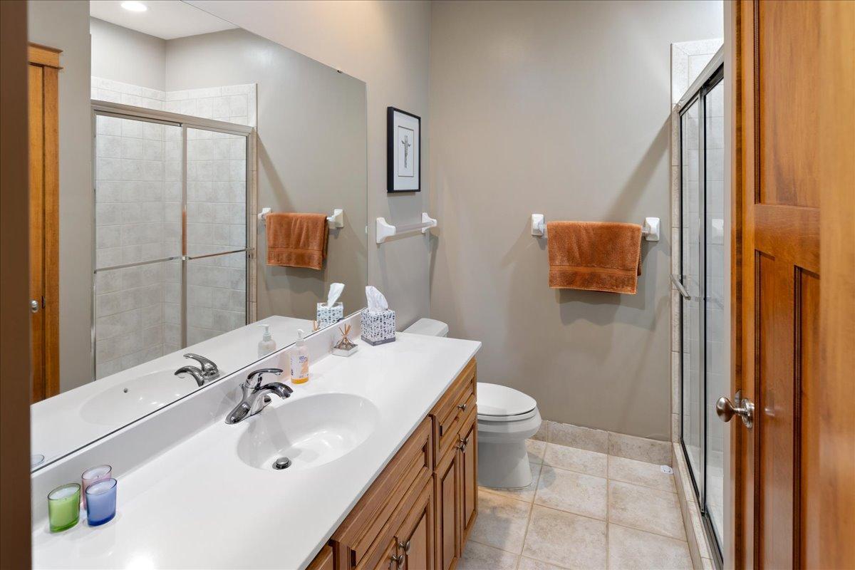 The well-appointed lower-level 3/4 bath offers a large linen closet for added storage, elegant ceramic tile flooring, and a tile shower surround, creating a comfortable and polished space for family and guests.