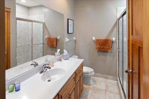The well-appointed lower-level 3/4 bath offers a large linen closet for added storage, elegant ceramic tile flooring, and a tile shower surround, creating a comfortable and polished space for family and guests.