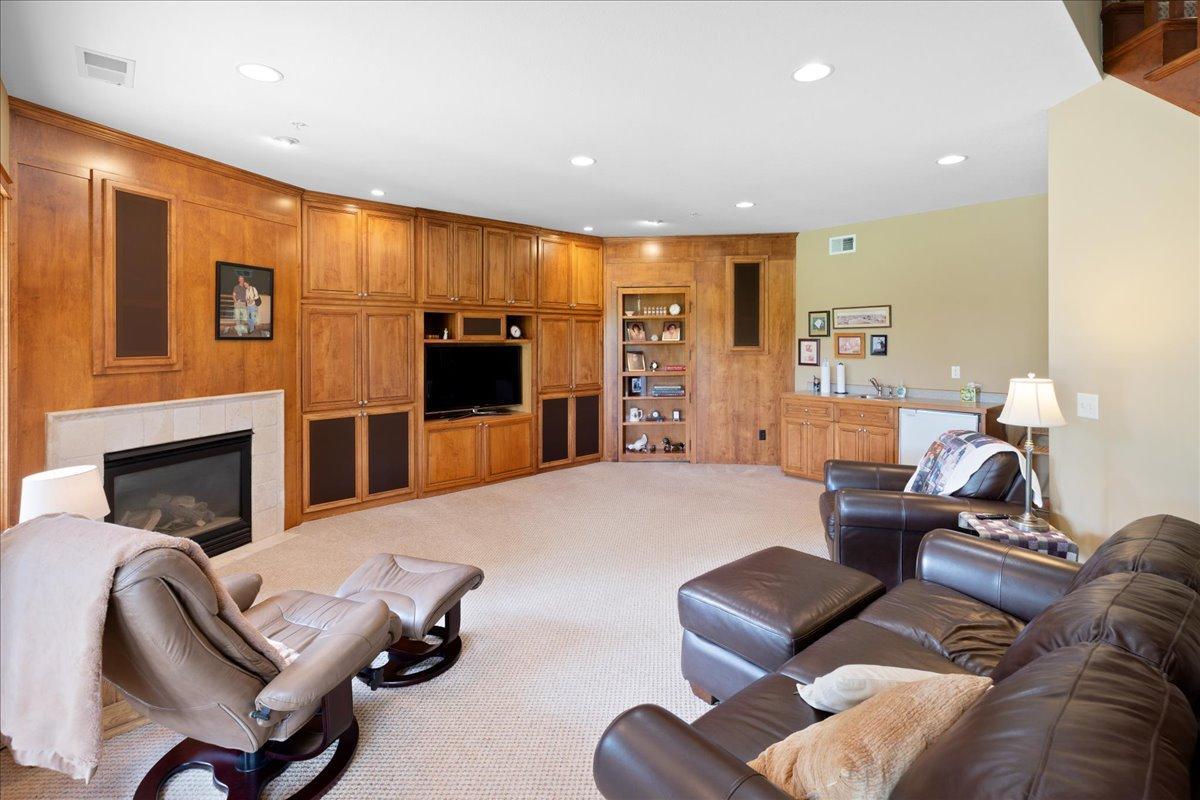 The lower-level family room is a warm and inviting retreat with cozy gas fireplace, full-wall entertainment cabinetry and surround sound. Both relaxation and entertaining, this space provides is perfect for movie night, gatherings, and everyday use.