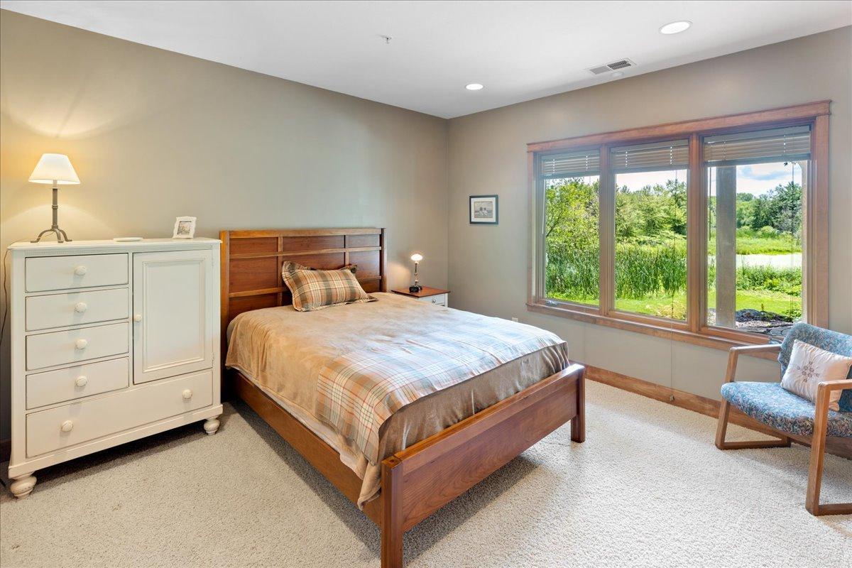 The larger lower-level bedroom is filled with natural light from a south-facing triple window set, creating a bright and inviting retreat with generous space and pleasant comfortable accommodations.