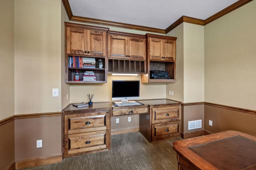Built-in desk and cabinetry provide added function, creating a versatile office with space to comfortably accommodate multiple work areas.
