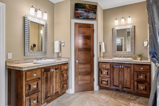 The private bath offers travertine floors, dual vanities, and a corner linen cabinet for excellent storage.