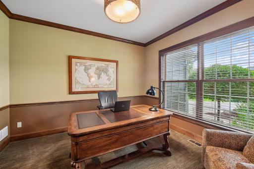 This private office features classic crown molding, chair rail accents, and a window with views to the front yard and entry.