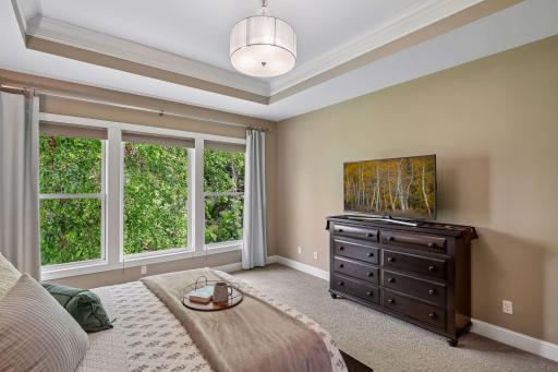 Like the living and dining rooms, the primary bedroom is filled with natural light from nearly floor-to-ceiling windows facing the private backyard.